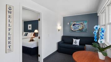 Een hotelkamer met een bed, een bank, een bijzettafeltje en een schilderij aan de muur.