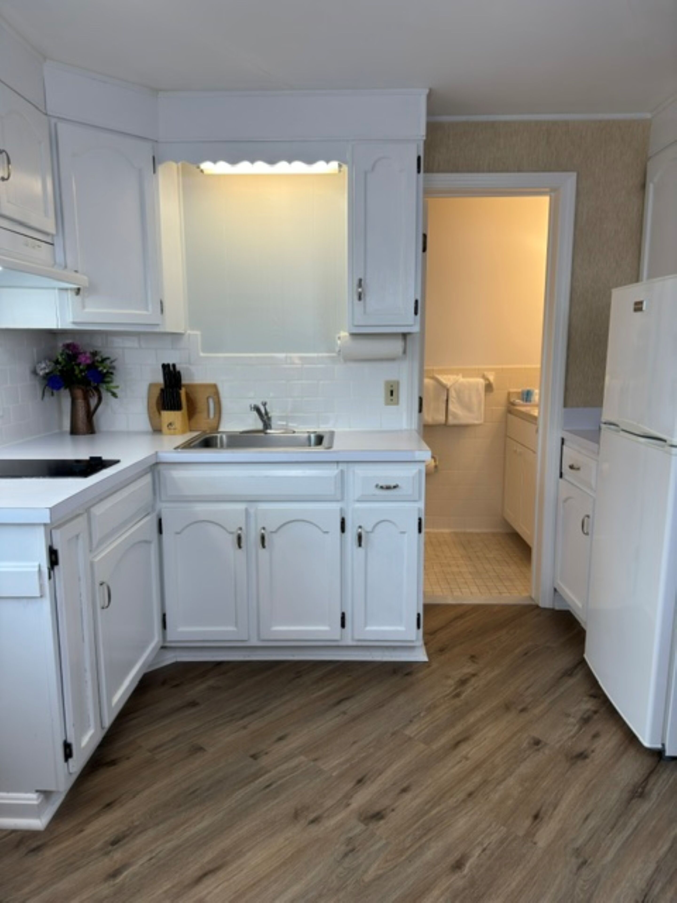 A kitchen with white cabinets, a sink, and a refrigerator.