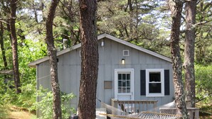 A cabin with a deck, a hammock, and a picnic table. - The Even'tide (Wellfleet)