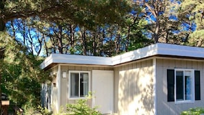 A small, single-story building with a flat roof, a front door, and a small porch area. - The Even'tide (Wellfleet)