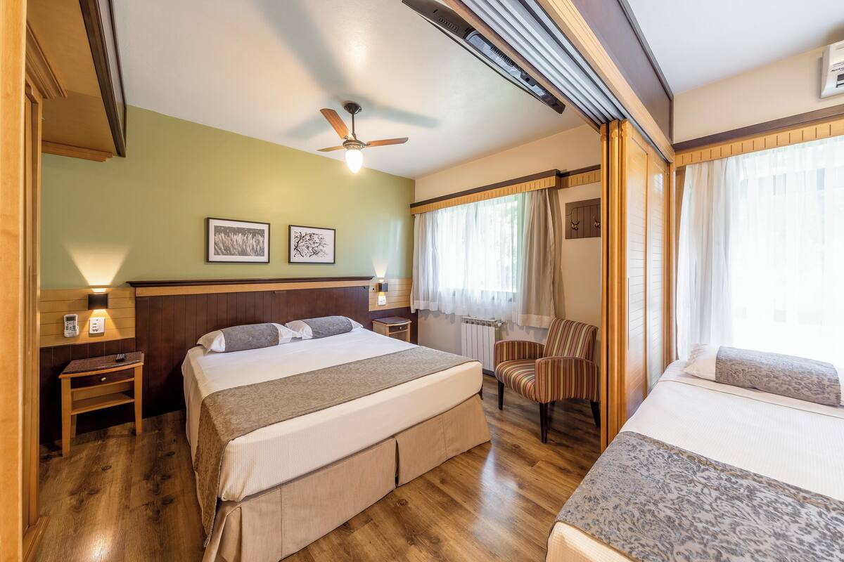 Una habitación de hotel con una cama grande, una silla, un escritorio y un ventilador de techo.