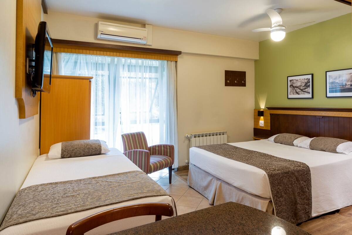 Una habitación de hotel con dos camas, televisión, una silla y una mesa.