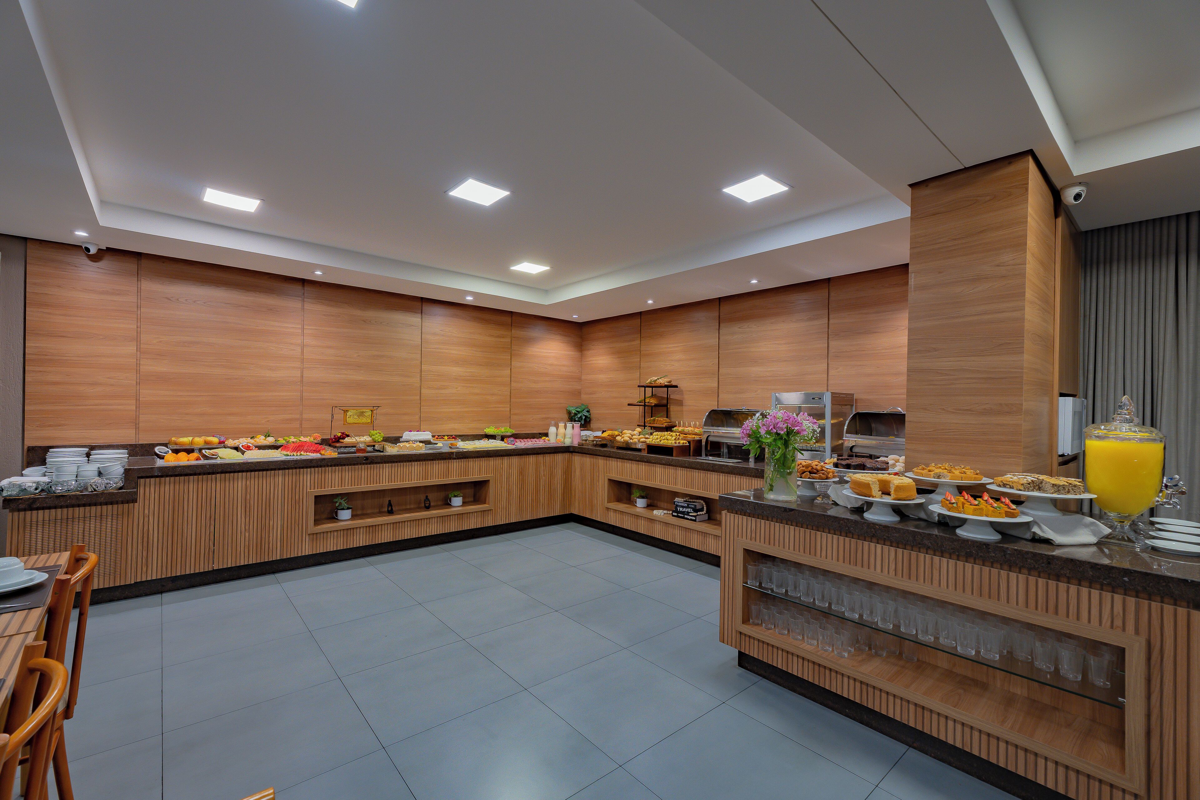A modern kitchen with wooden cabinets, a buffet counter, and a juice dispenser.