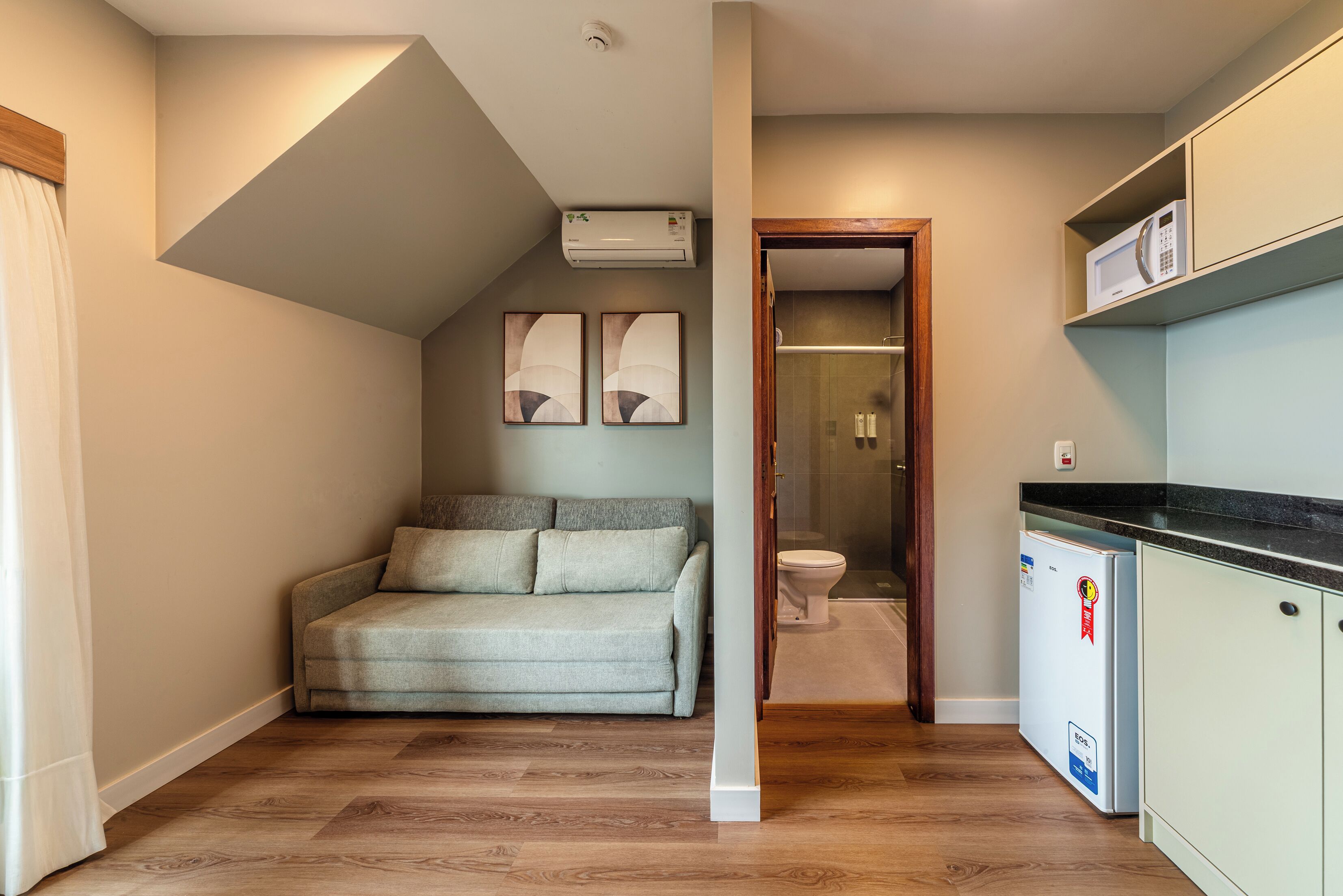 A compact living space with a sofa, a kitchenette, and a shower area.