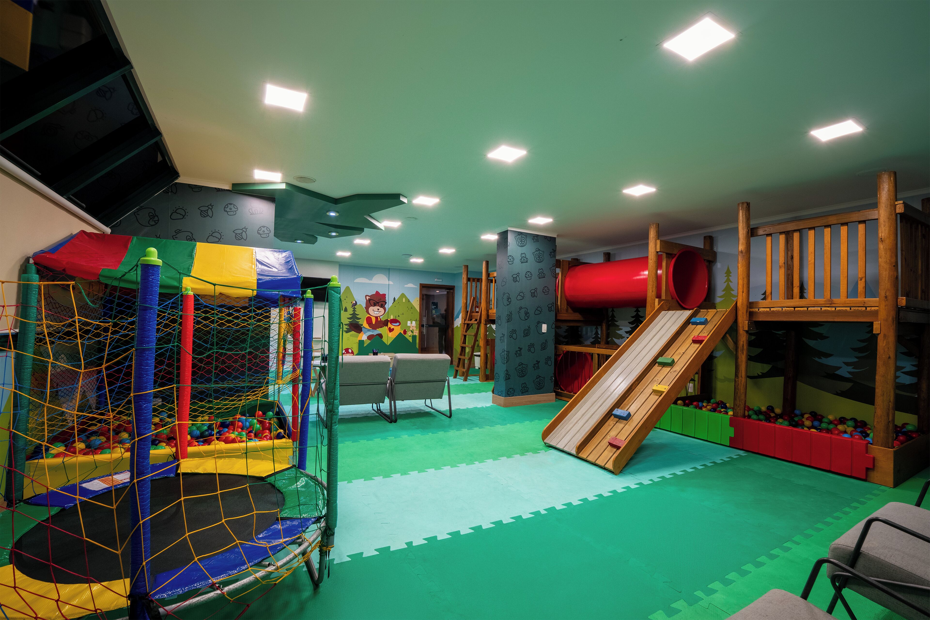 Zona de juegos con una red de escalada, un tobogán y una piscina de pelotas.