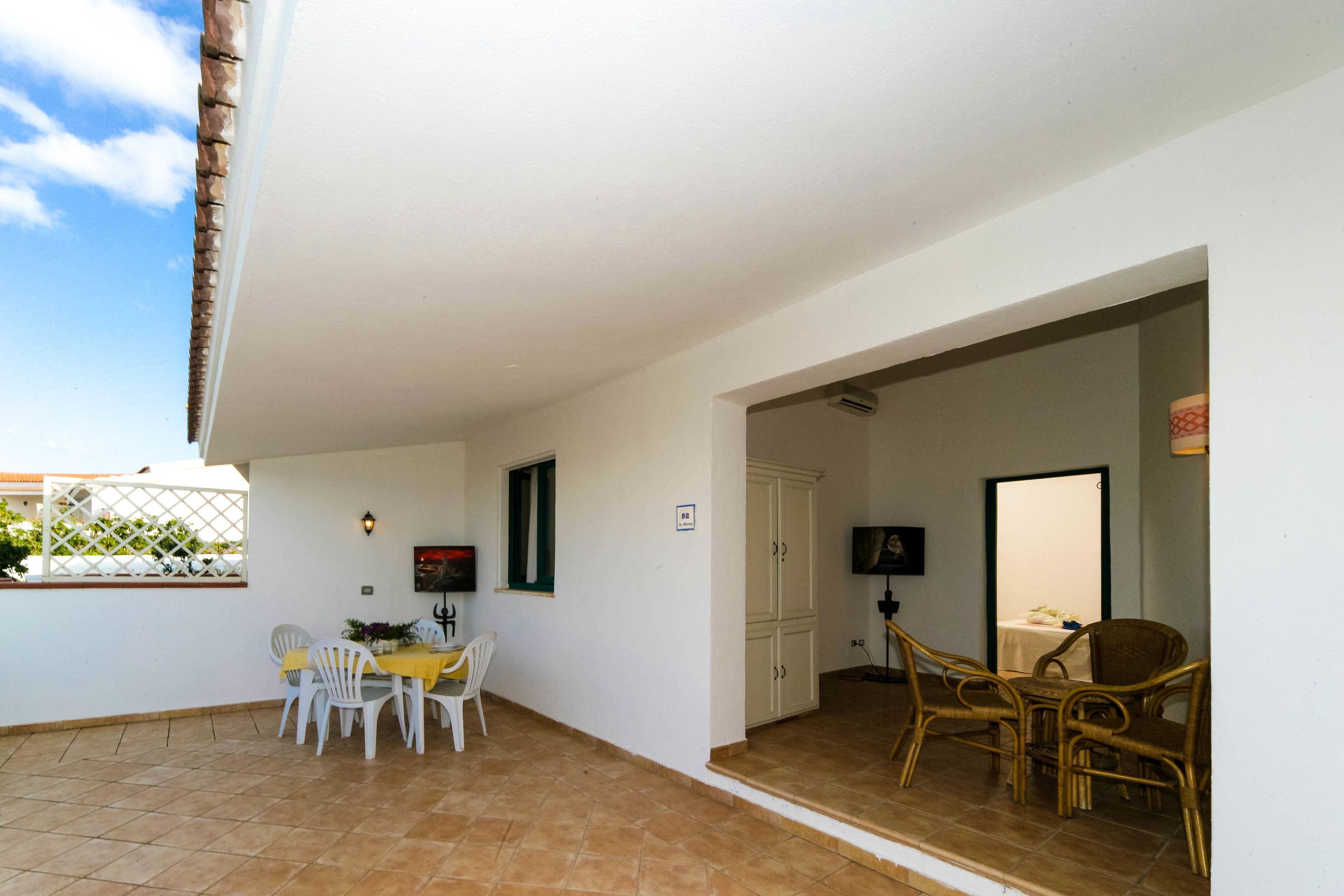 Un espace patio comprenant une table et des chaises pour les repas, un téléviseur et un meuble de rangement.