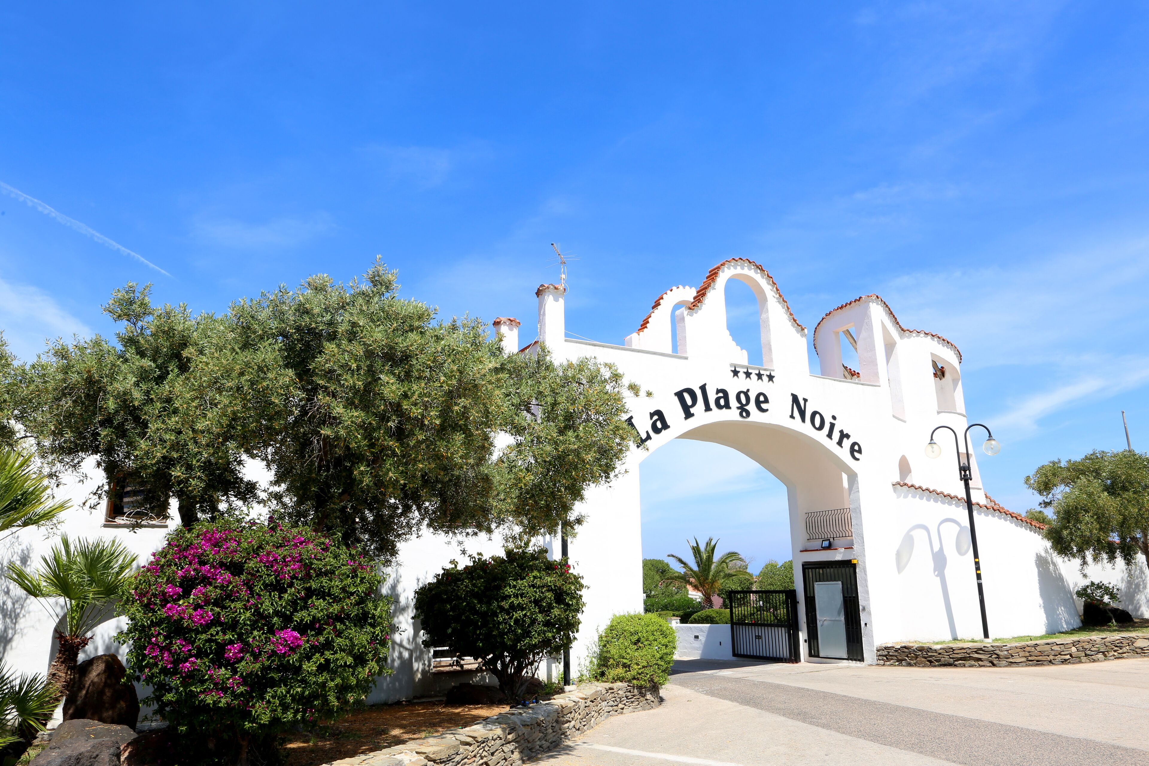 A white building with an arched entrance labeled "La Plage Noire".
