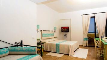 A bedroom with two beds, a dining area, and a view of the sea.