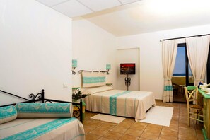 A bedroom with two beds, a dining area, and a view of the sea. - La Plage Resort (Sorso)
