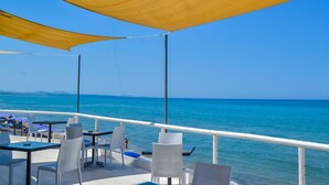 A deck with tables and chairs overlooking a calm sea. - La Plage Resort (Sorso)
