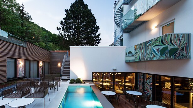 Un área de piscina exterior moderna con asientos y un bar.