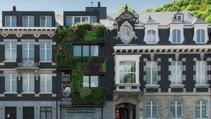 A multi-story building with a mix of modern and classic architectural styles, featuring balconies, large windows, and a sign for "The Royal Nail Hotel".