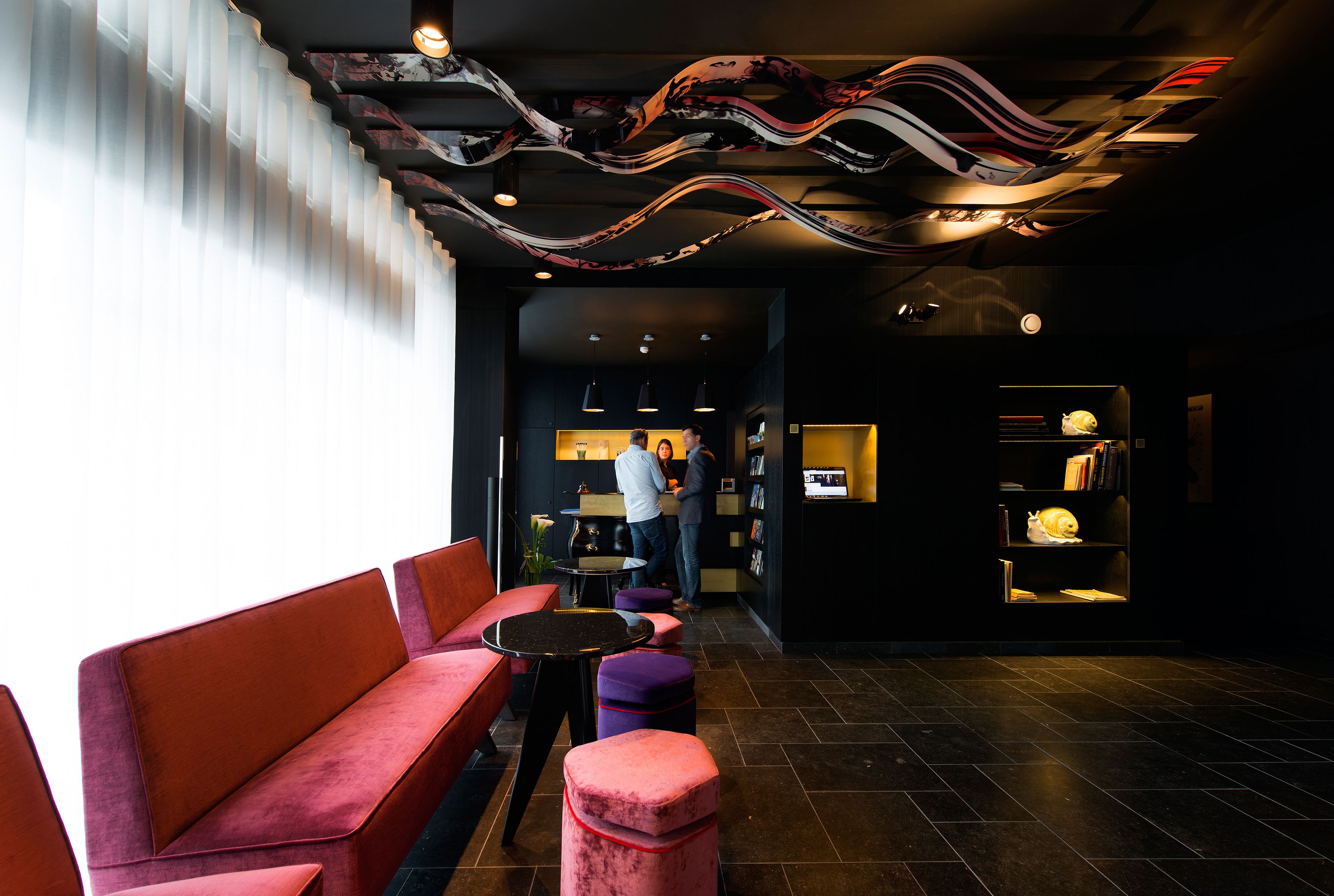 A modern interior with a seating area, a reception desk, and a bookshelf.
