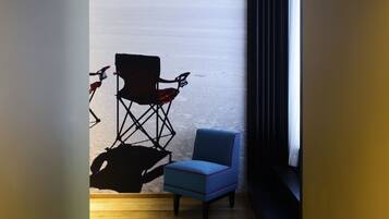 A narrow hallway with a wooden floor, a blue chair, and a director's chair.