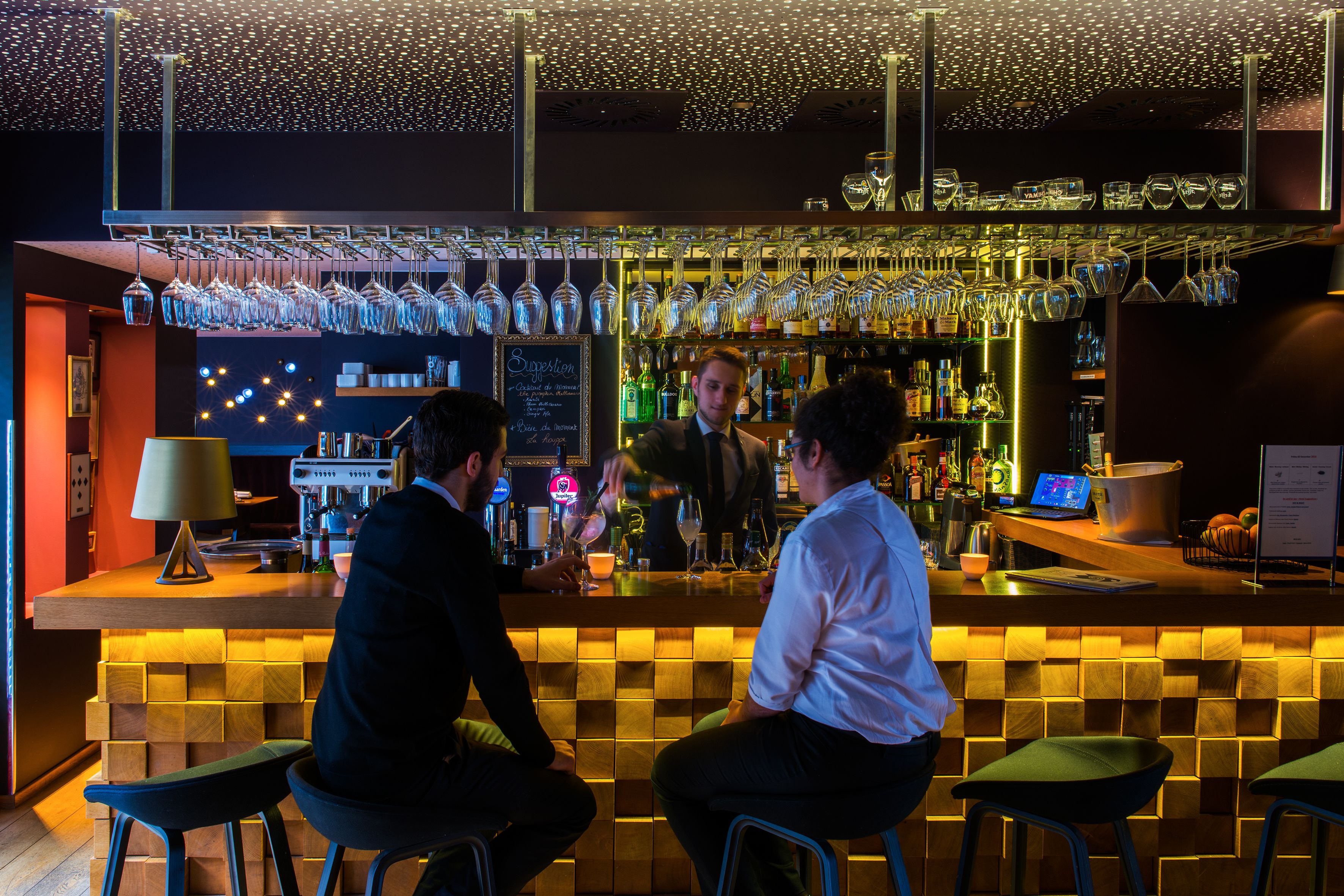 A bar with stools, a bartender, and a well-stocked bar counter.