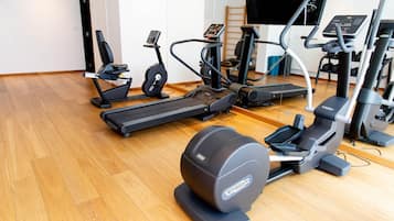 Un gimnasio con diferentes máquinas de ejercicio, una cinta de correr y una bicicleta estática.