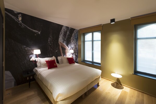 Un dormitorio moderno con una cama grande, dos lámparas de noche, una mesita de noche y un ventanal con vistas.