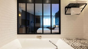A modern bathroom with a large mirror, a bathtub, a towel rack, and patterned floor tiles. - Hotel Leo Station et Annexes (Bastogne)