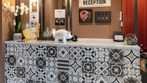 A reception area with a tiled counter, a reception sign, and a pig-shaped decoration. - Hotel Leo Station et Annexes (Bastogne)