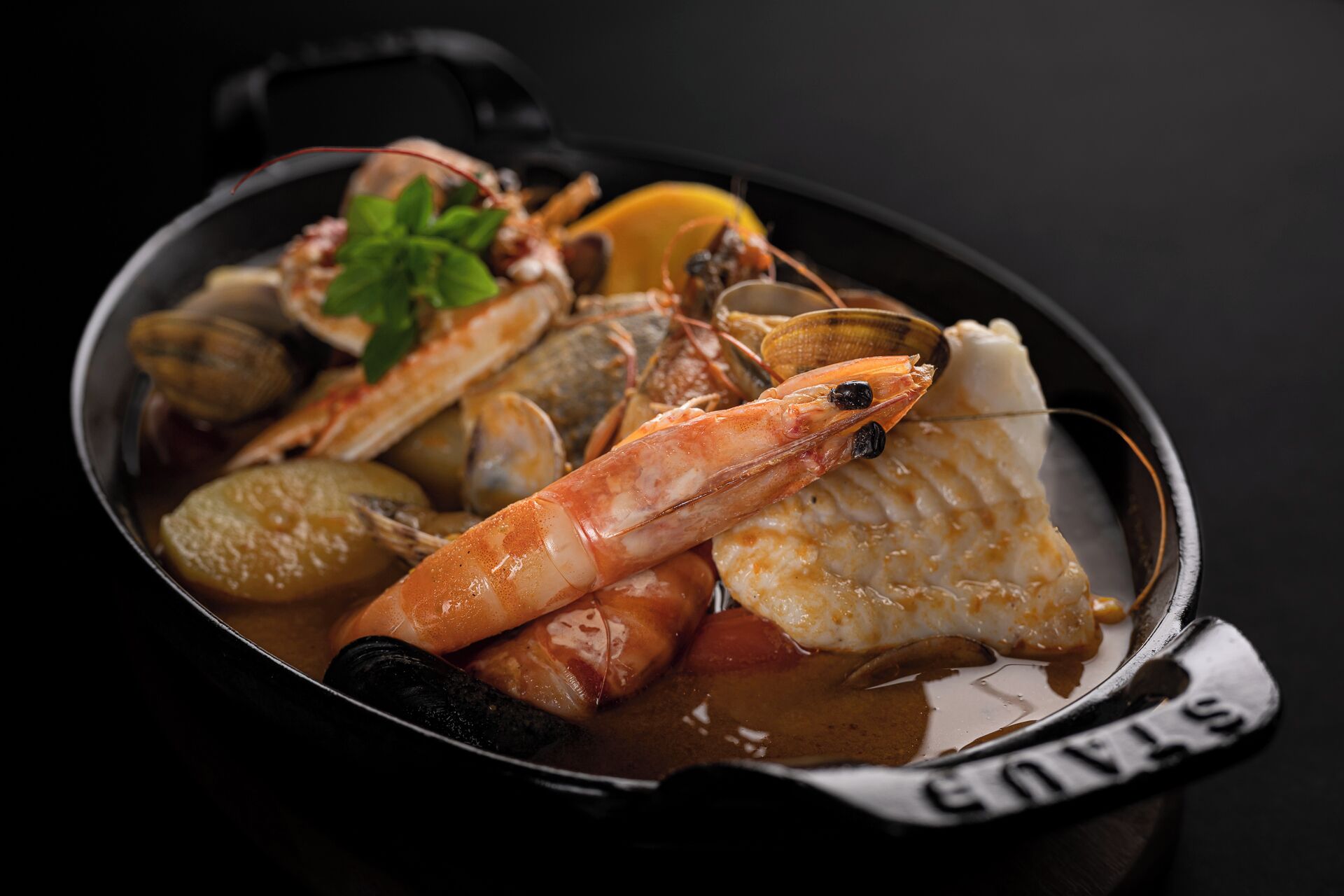 A seafood dish in a black pot with a handle.