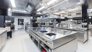 A modern commercial kitchen with stainless steel appliances, a central island, and a tiled backsplash. - Hotel Leo Station et Annexes (Bastogne)