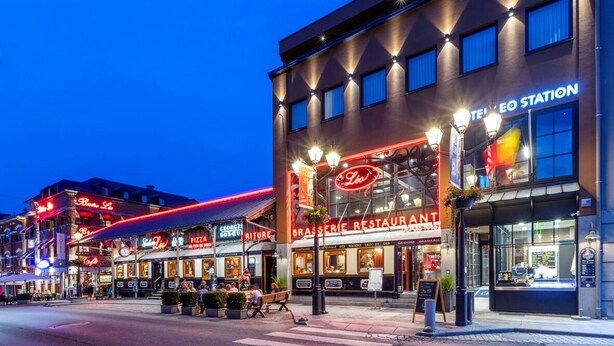 A building with multiple restaurants, including a visible 'Brasserie Restaurant' sign. - Hotel Leo Station et Annexes (Bastogne)