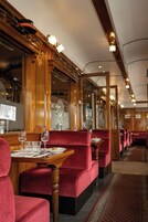 Un restaurante con paneles de madera, cabinas de terciopelo rojo y una larga mesa de comedor con vasos y platos.