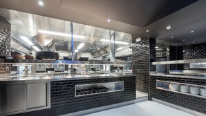 A modern kitchen with stainless steel appliances, a brick accent wall, and a clean, organized layout. - Hotel Leo Station et Annexes (Bastogne)