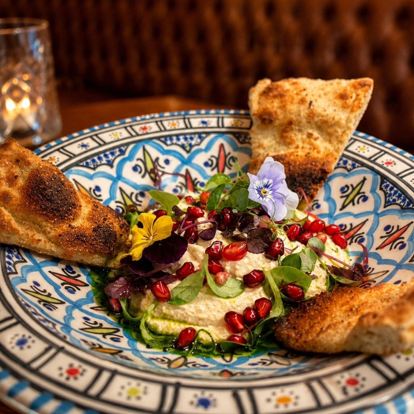 Een bord met een salade, granaatappelpitjes en een stuk brood.