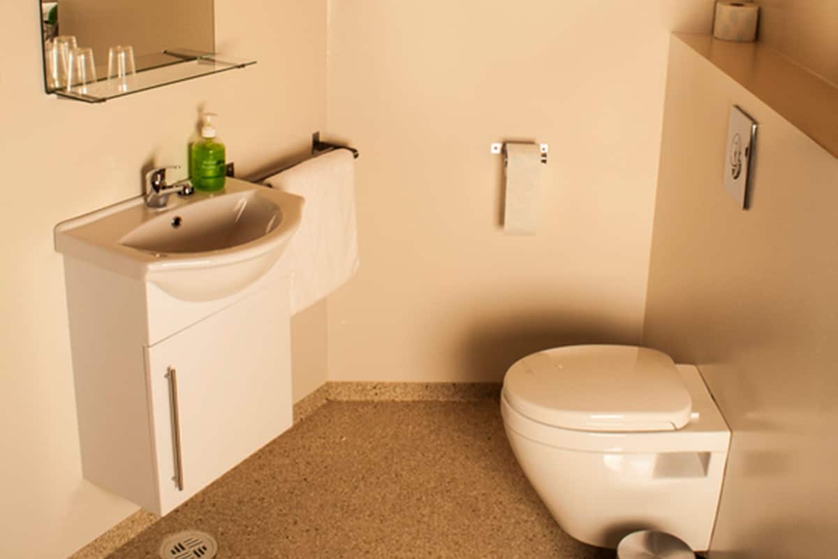 Un baño pequeño con techo de madera, un lavamanos blanco, un espejo y un inodoro.