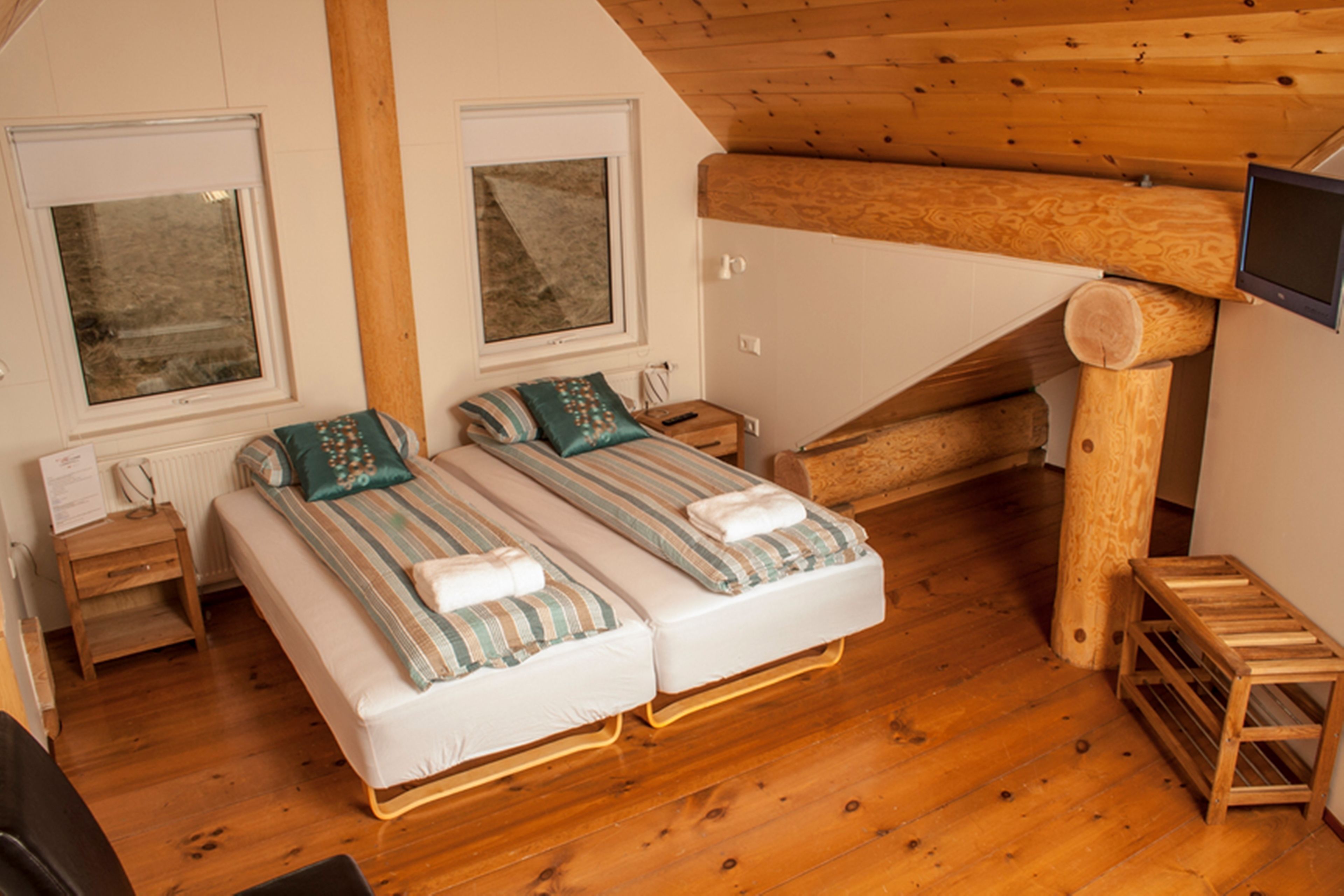 Une petite pièce agréable, dotée de deux lits, d’un plancher en bois et d’un plafond en pente.