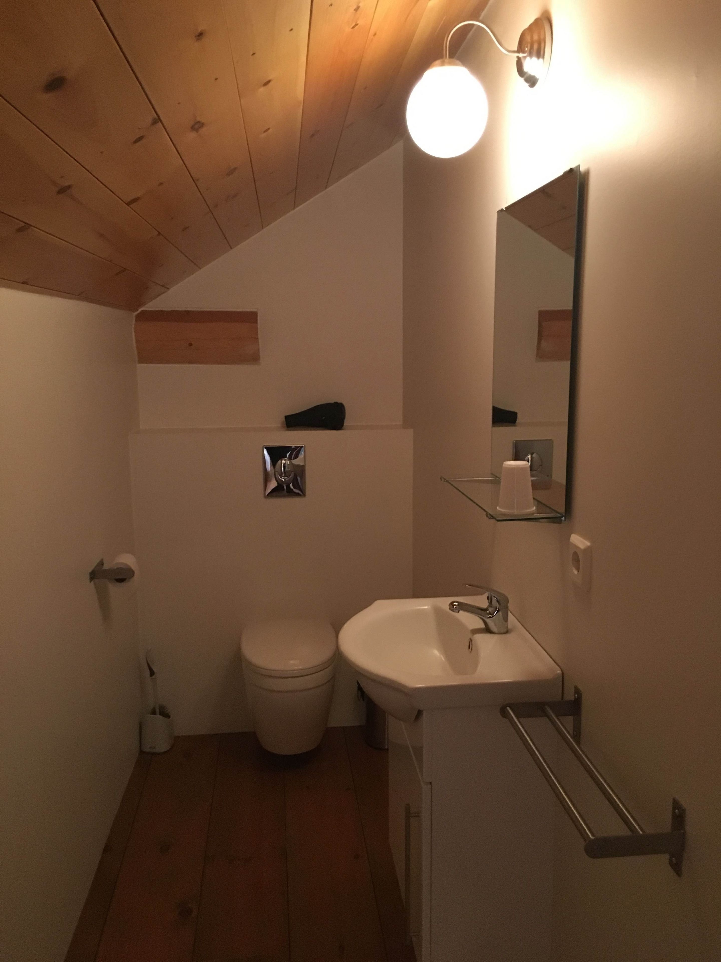 A compact bathroom with a toilet, sink, and mirror.