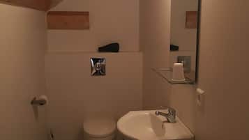 A compact bathroom with a toilet, sink, and mirror.