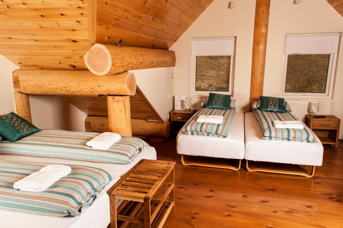 Una habitación acogedora de estilo cabaña con dos camas, vigas de madera y un ambiente rústico.
