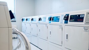 A row of commercial-grade front-loading washing machines in a laundry facility. - Residence & Conference Centre - North Bay (North Bay)