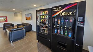 A lobby with two vending machines labeled "COLD DRINKS" and a seating area with leather chairs. - Residence & Conference Centre - North Bay (North Bay)