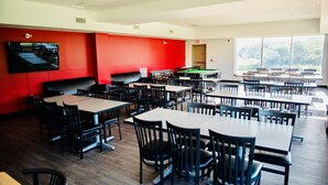A spacious dining area with multiple tables and chairs, a pool table, and a television mounted on the wall. - Residence & Conference Centre - North Bay (North Bay)