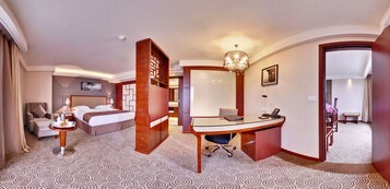 Habitación de hotel con cama, escritorio, silla y un espejo grande.