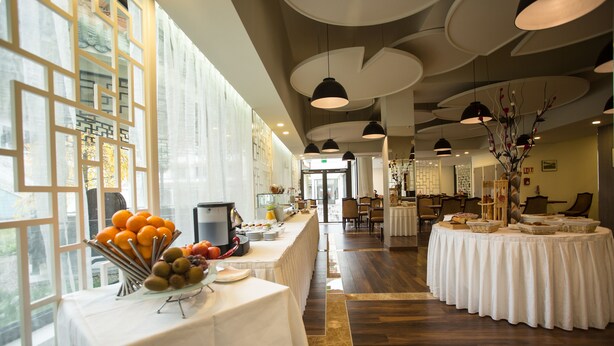 A spacious hotel lobby with a long reception desk, large windows, and modern pendant lighting. - Huatian Chinagora Hotel (Alfortville)