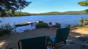 A lakeside view with a dock, chairs, and a clear sky.