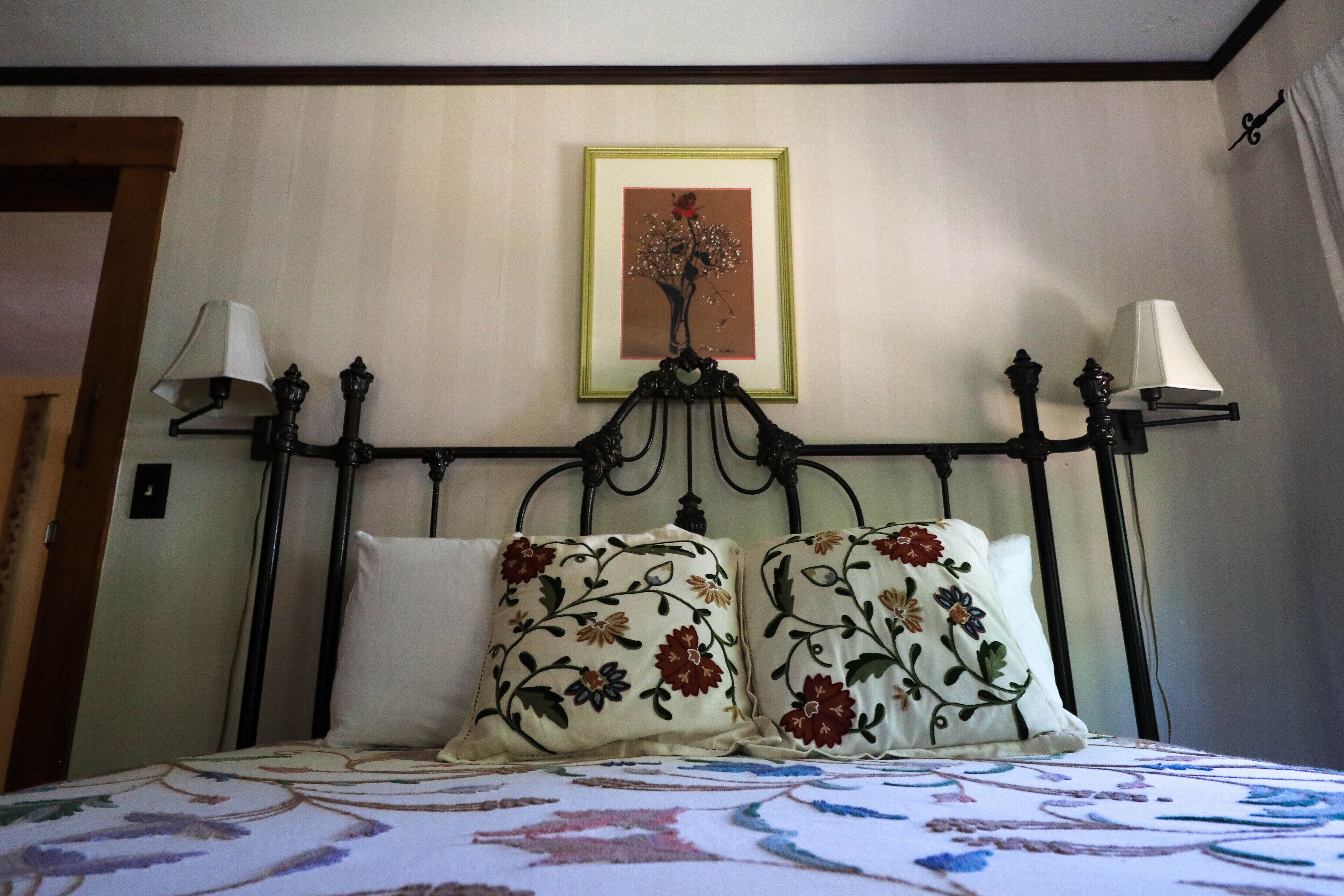 Cama bem arrumada com almofadas estampadas e uma obra de arte emoldurada acima.