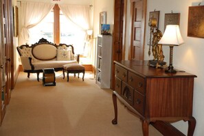 A room with a sofa, a wooden cabinet, a lamp, and a statue.