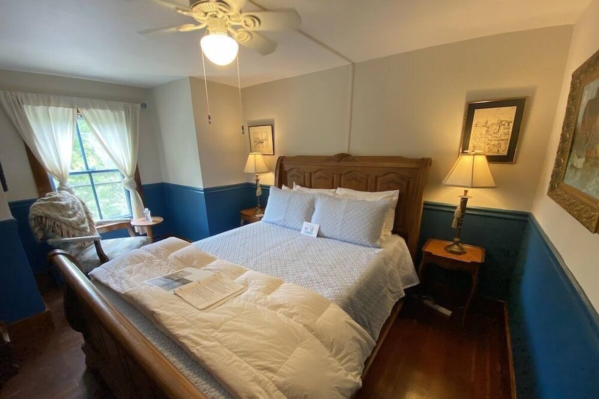 A neatly made bed with a wooden headboard, two bedside lamps, and a ceiling fan.