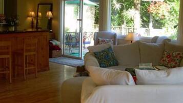 A living room with a white sofa, a wooden coffee table, and a kitchen area with a counter and cabinets.