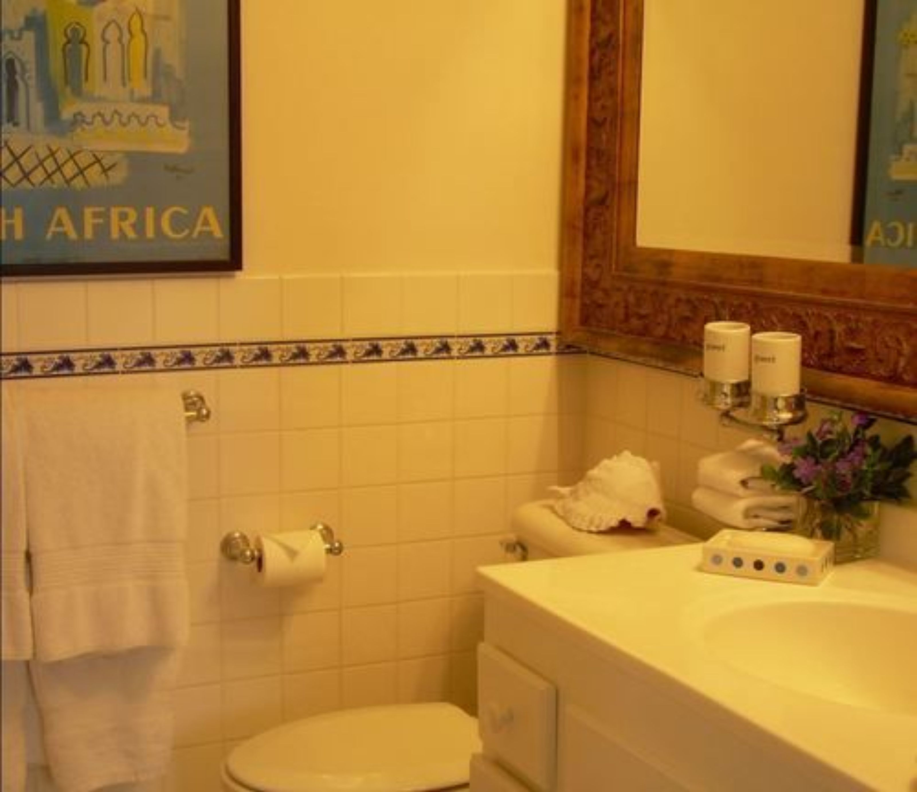 Une salle de bain avec des toilettes, un lavabo et un miroir. On y trouve des serviettes et des articles de toilette sur le lavabo.