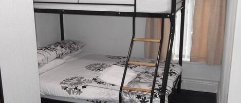 A bunk bed with a floral-patterned bedspread and a white pillow on the top bunk.