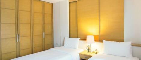 Une chambre d’hôtel avec deux lits, une armoire en bois et une lampe de chevet.