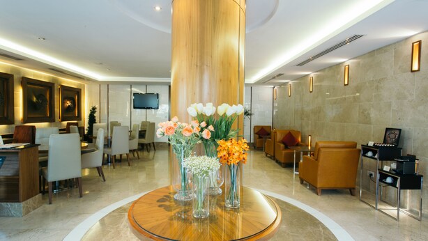 Un vestíbulo moderno con una columna de madera central, zonas de estar y una recepción.