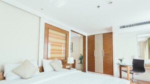 Una habitación de hotel con una cama grande, un escritorio con una silla y un armario.