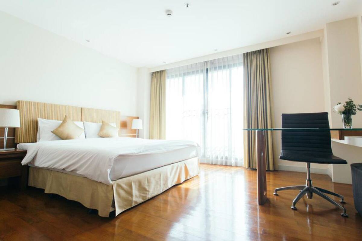 Ein Hotelzimmer mit einem großen Bett, einem Schreibtisch mit Stuhl und einem Fenster mit Vorhängen.